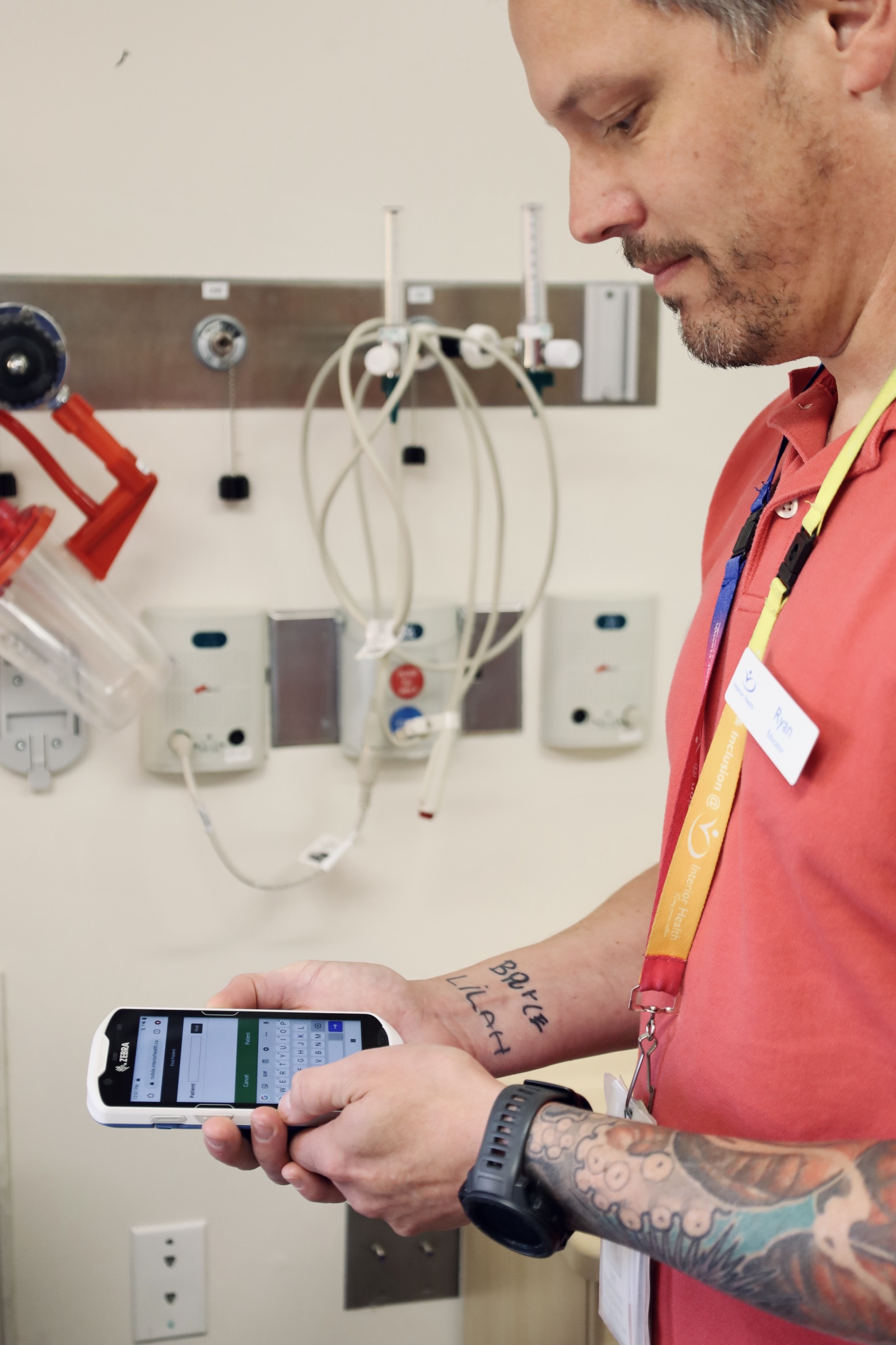 A male nurse holds a handheld device to analyze medical results for patients