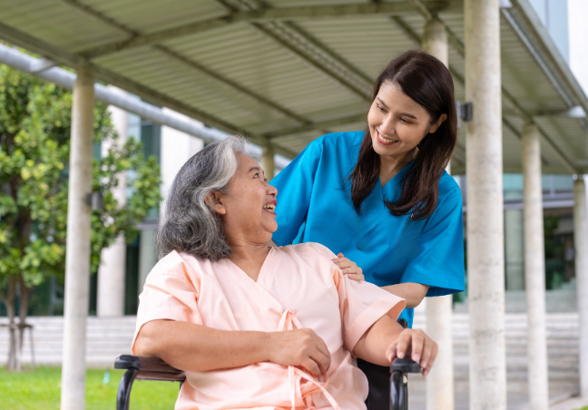 Woman helping senior woman on wheelchair while smiling