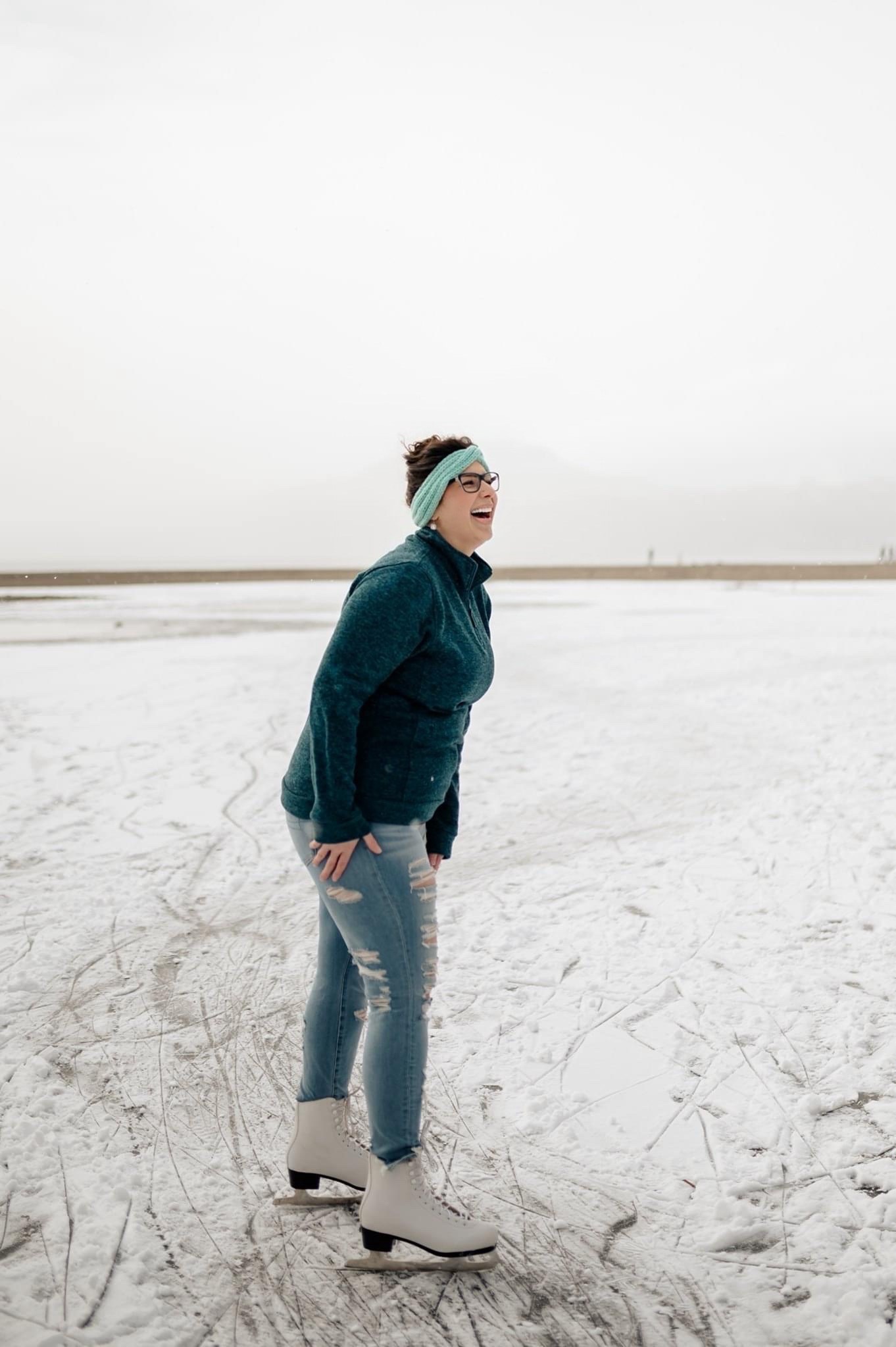 Woman ice skating outside laughing.