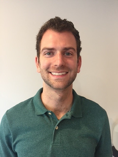 a smiling doctor with brown hair looking at the camera