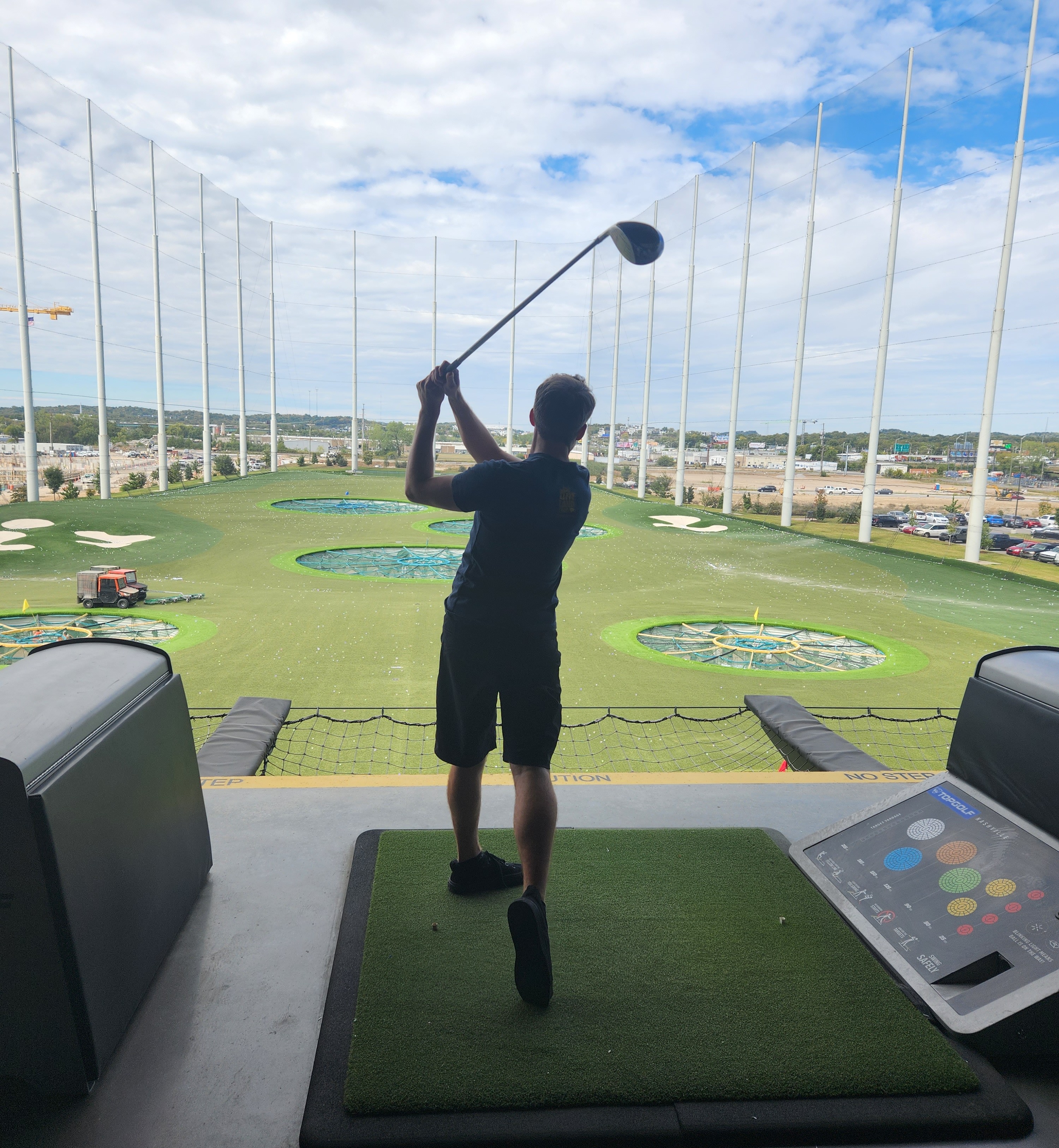 Man hitting golf balls at driving range.