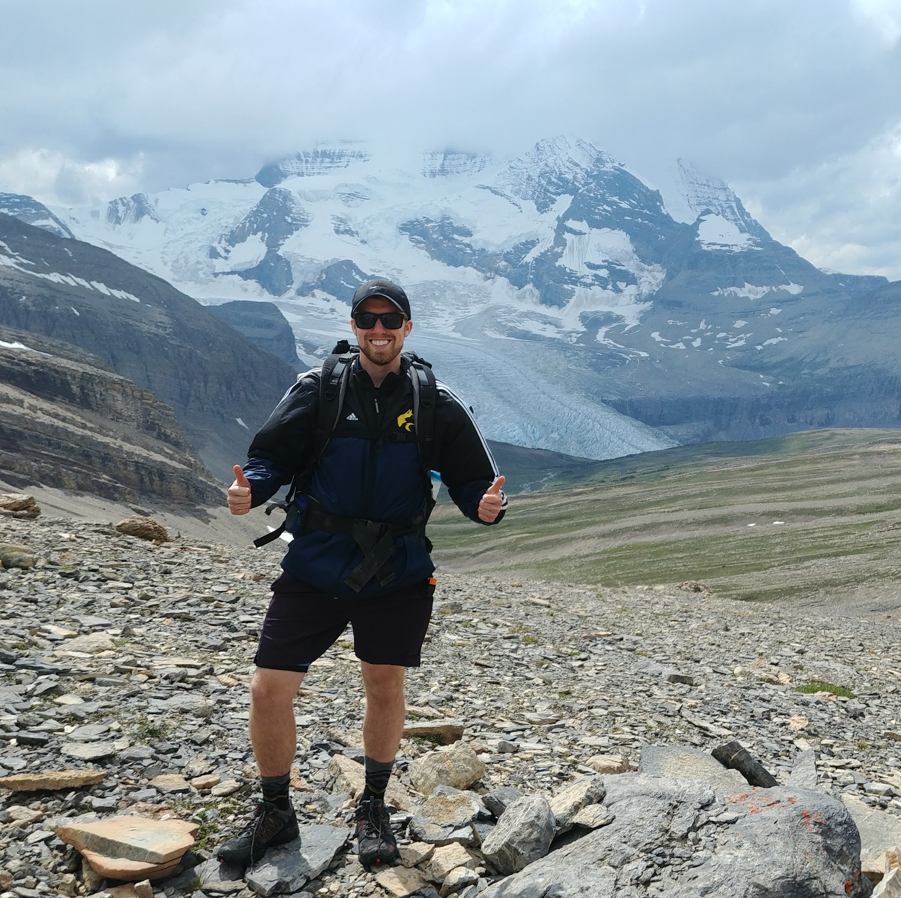 Man hiking with snow-covered mountains in the background.