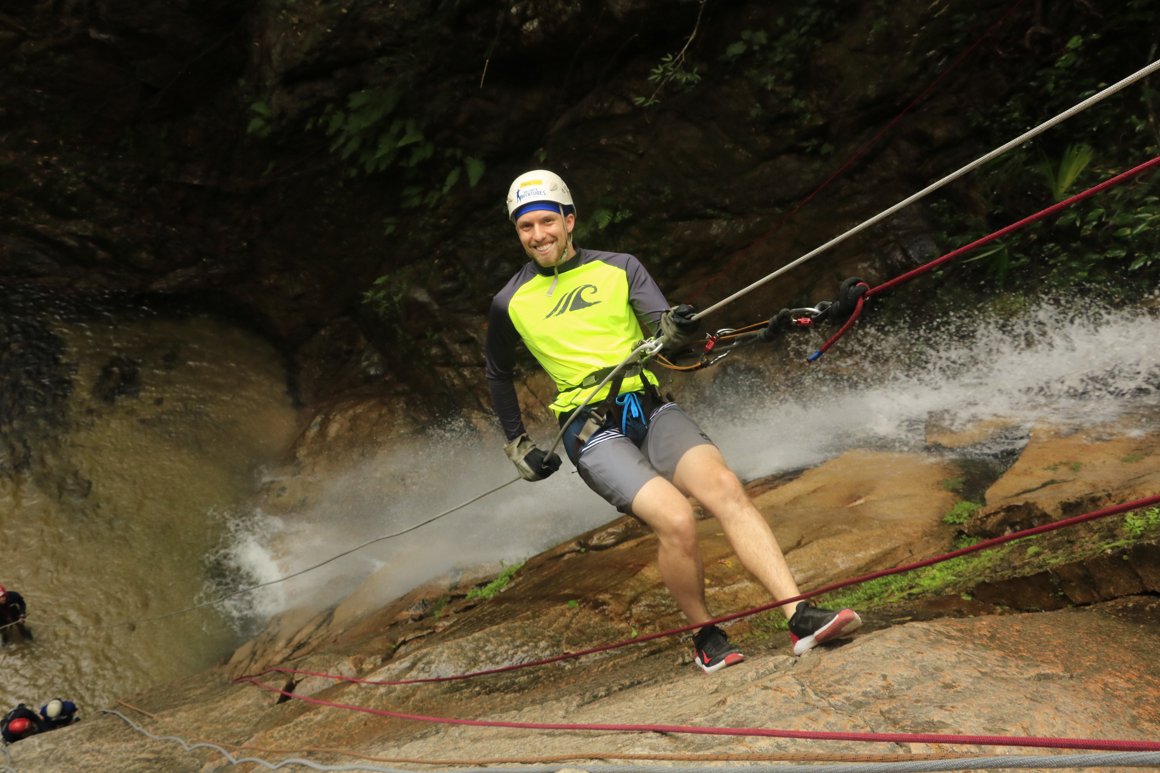 Man hangs off rock face while rock climbing.