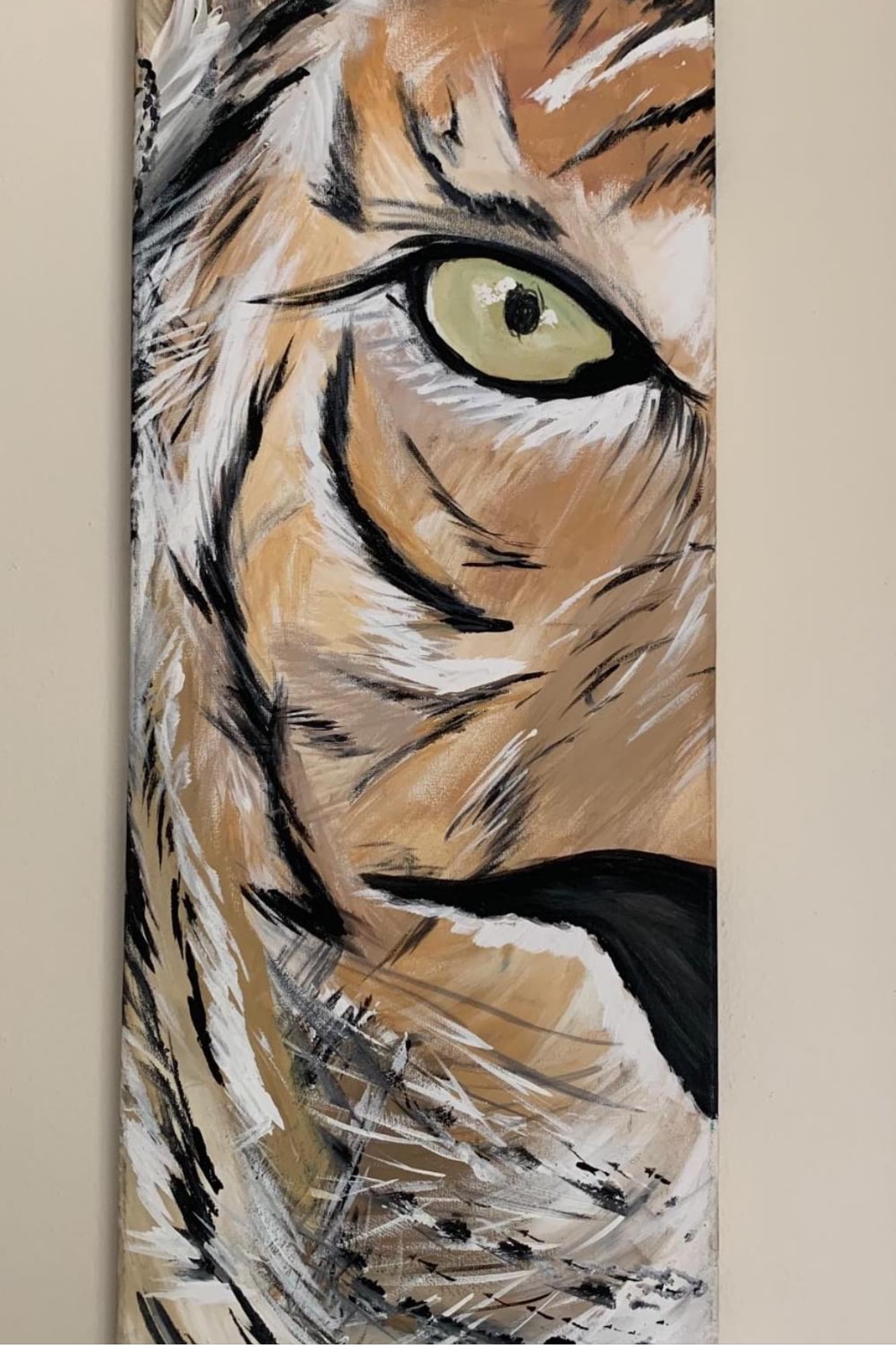 A painting showing half the face of a tiger with green eyes