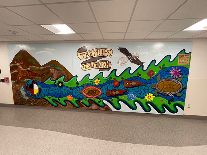 A colourful mural depicting a mountain, animals and a stream using Indigenous imagery