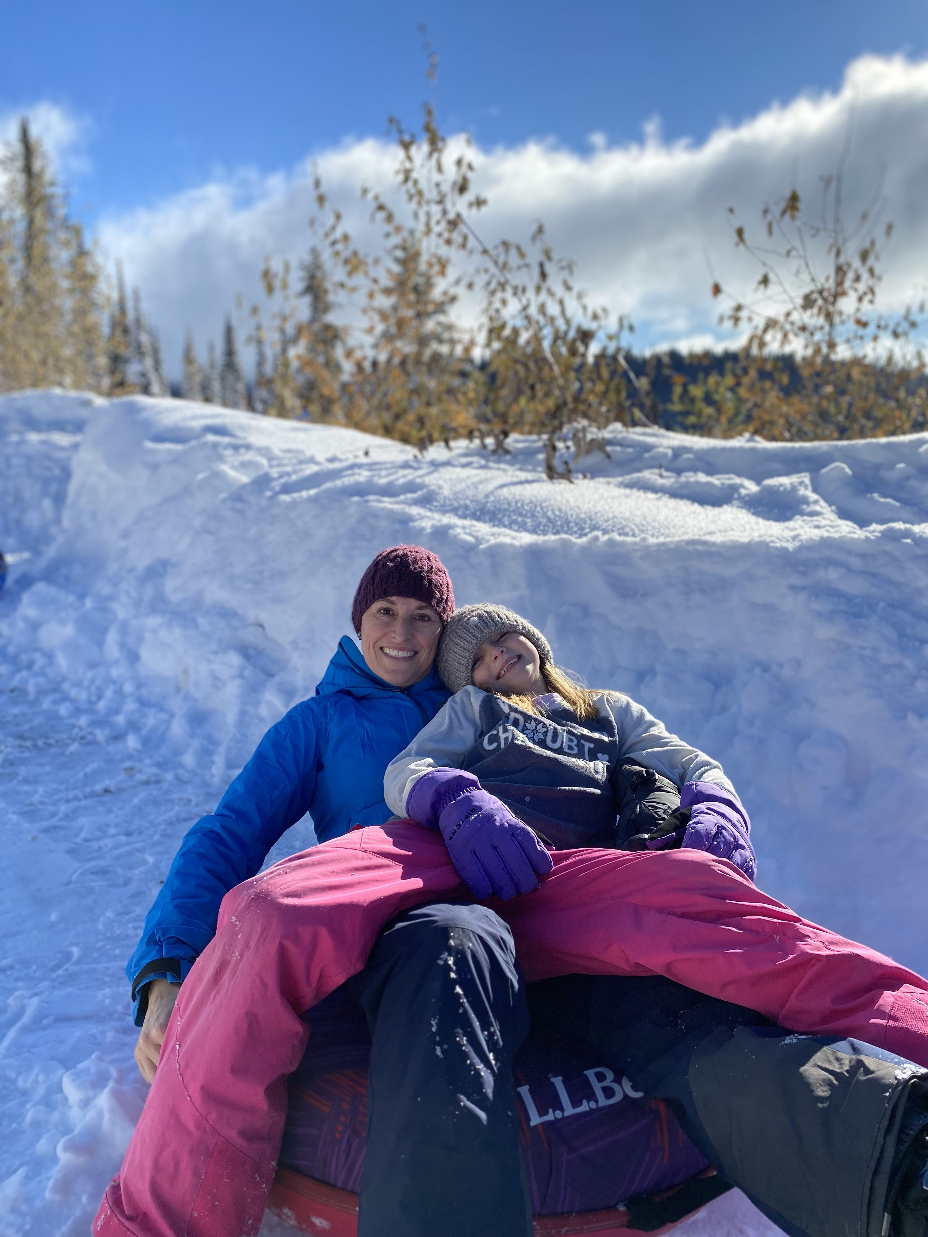 A mother and her daughter play in the snow.