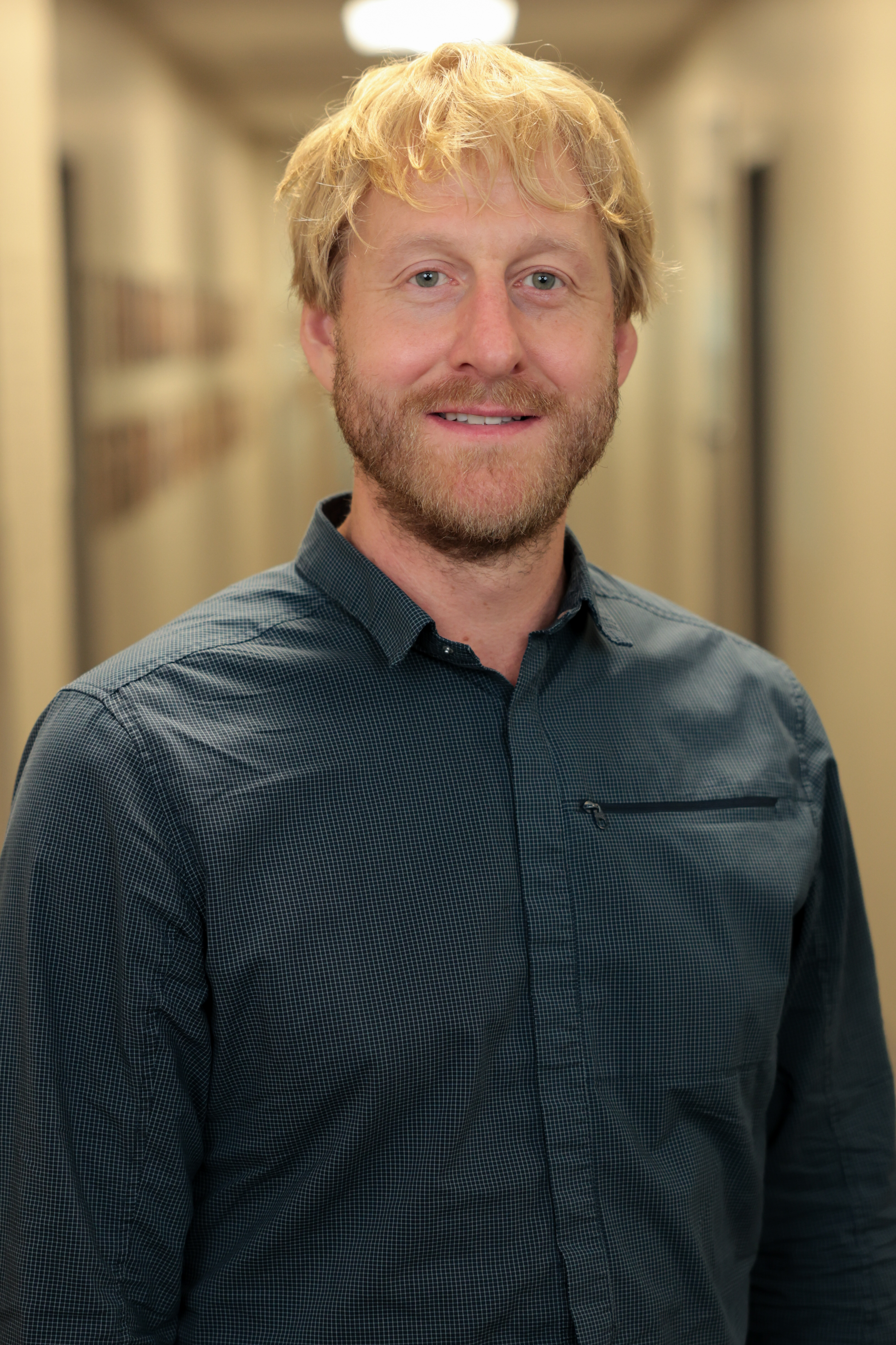 A profile shot of a smiling man with blonde hair and beard, who is wearing a business shirt. 