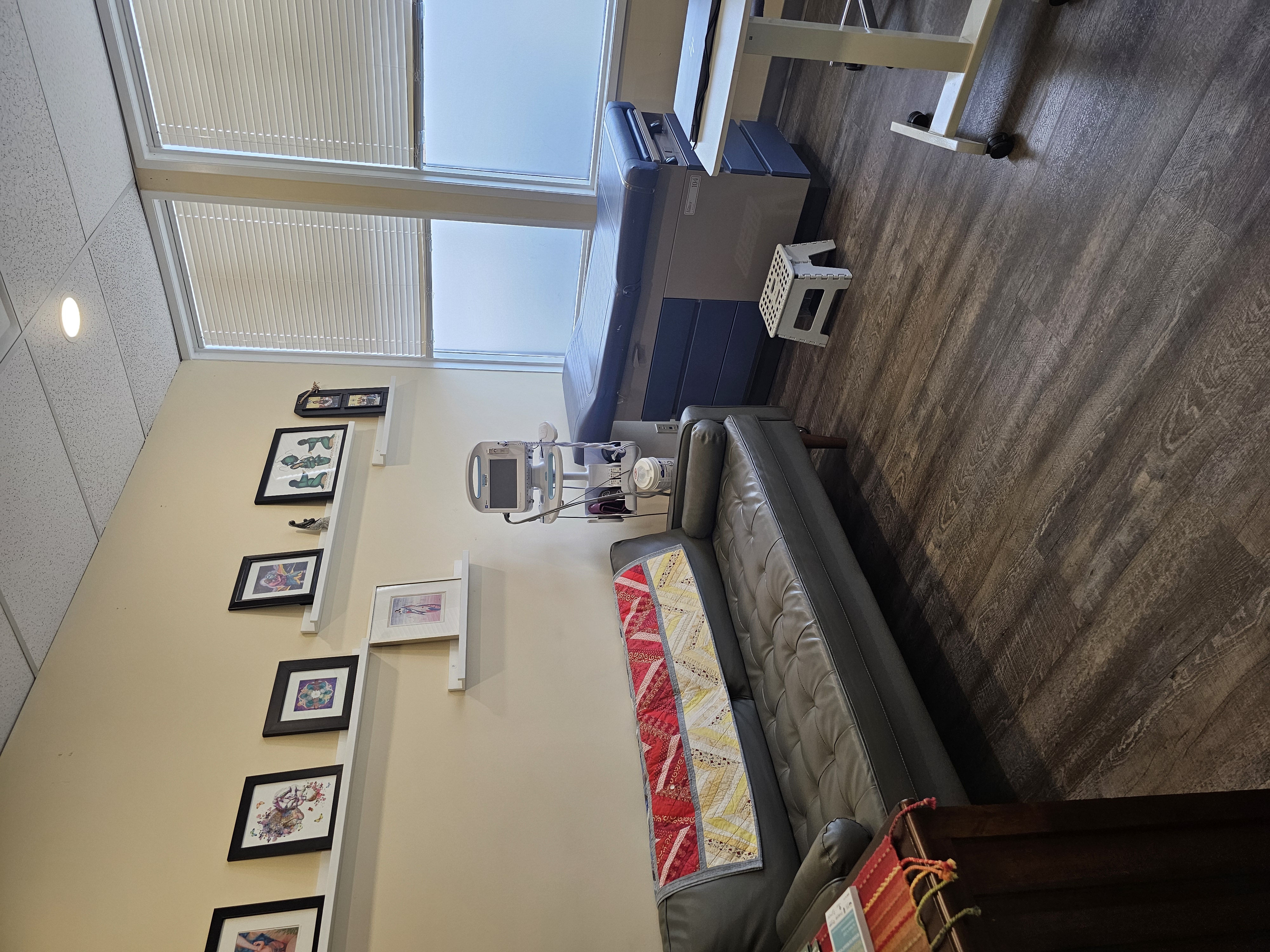 An examination room featuring a couch, exam bed and medical equipment.