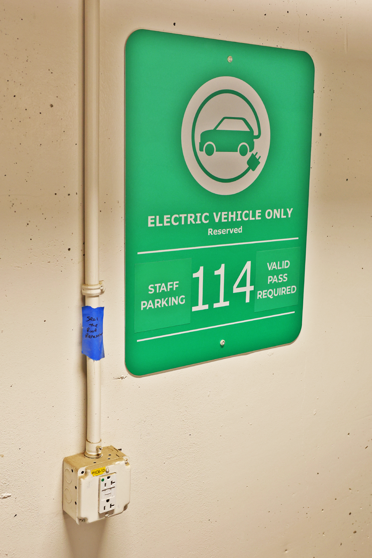 A green sign that says electric vehicle only next to an outlet