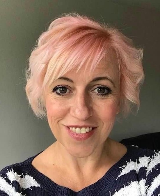 Woman with short pink hair in black and white striped top