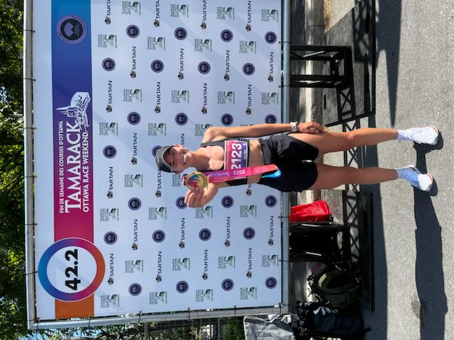 Woman standing in running gear holding a medal