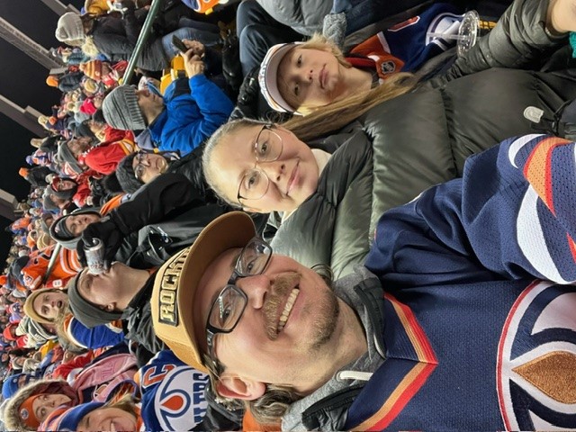 Man, woman, and boy sitting in a crowd at sporting event