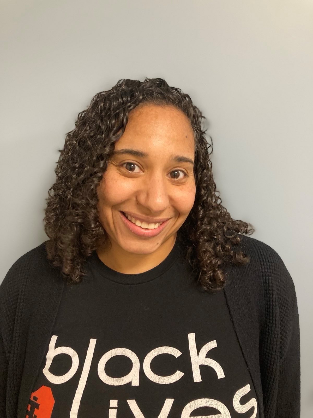 A Black woman with curly dark hair smiling for the camera 