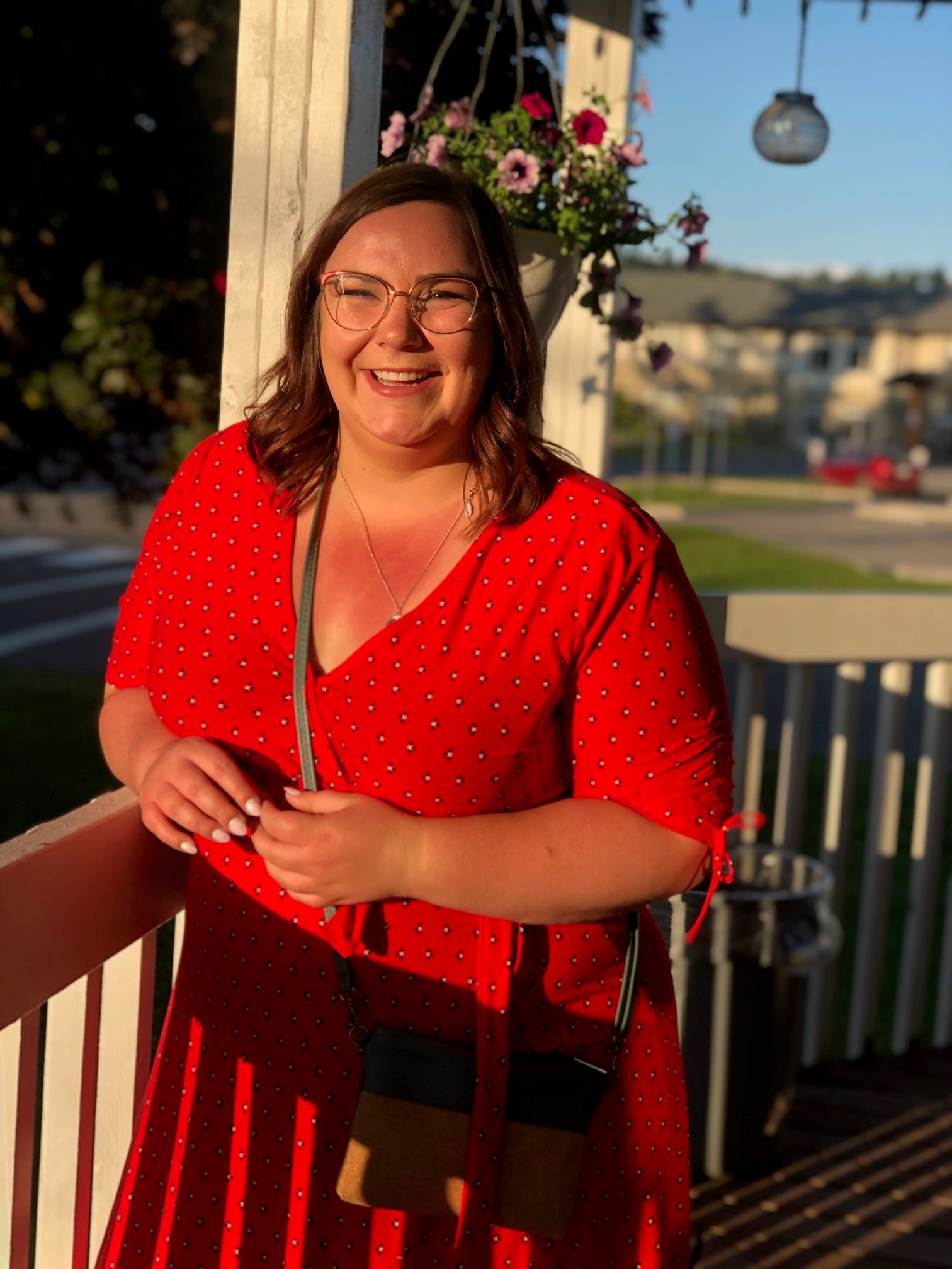 Woman in red dress standing on a porch on a summer evening