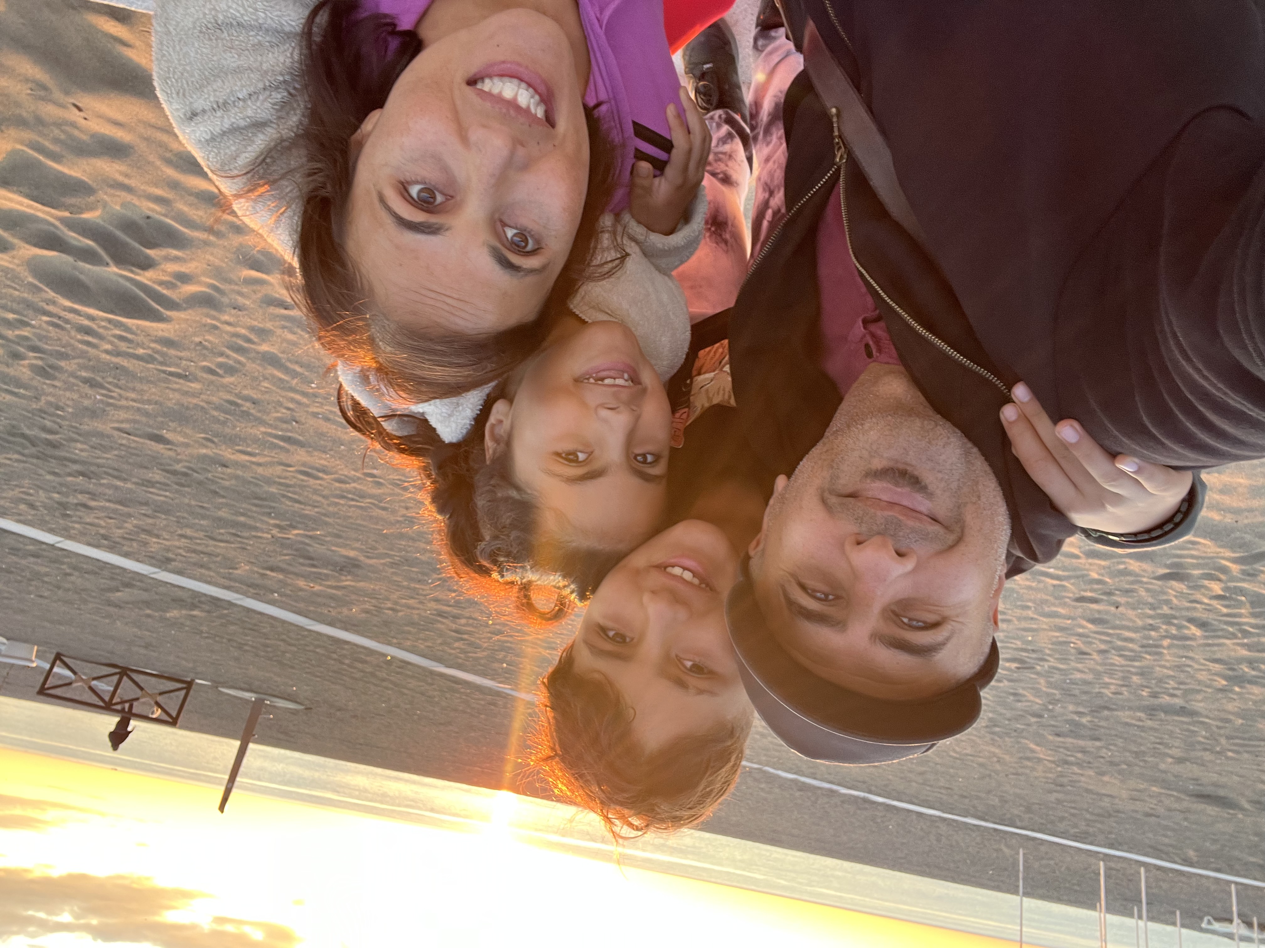 Woman and man with two children on a beach during sunset