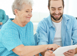 A senior lady and a younger man use technology to access health-care information.