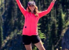 Woman hiking in mountains making peace sign.