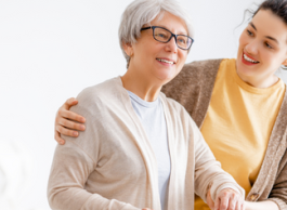 A senior using a cane is supported while walking by a younger person.