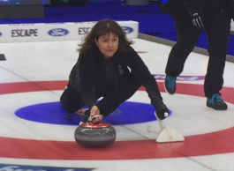 A person throws a curling stone.