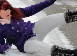 A woman slips and falls on an icy sidewalk.