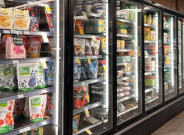 Frozen food displayed in a glass-enclosed freezer at a grocery store.