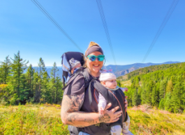 woman with infant in carrier on her back, and another on her front going for a hike