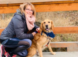 A women kneeling behind a dog with reddish fur