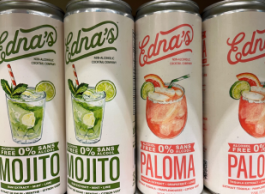 Four white cans of Edna's non-alcoholic mojitos and palomas sit on a grocery shelf