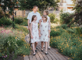 A family, a woman, a man and two young girls in front of a garden.