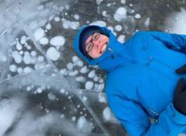 Man in blue jacket lying on frozen lake