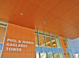 The entrance to a building framed in orange coloured wood and glass with signage that says Phil and Jennie Gaglardi Tower