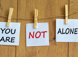 Three notes attached by clothespins to a wire that say You are not alone