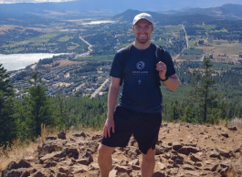 Man poses for picture on a hike with beautiful background.