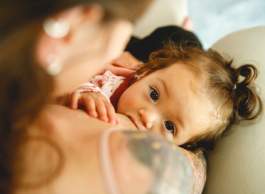 Infant child looking over parent’s shoulder while breastfeeding