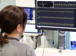 Health-care professional monitoring a patient's vital signs on a Dell computer screen displaying multiple charts and graphs.